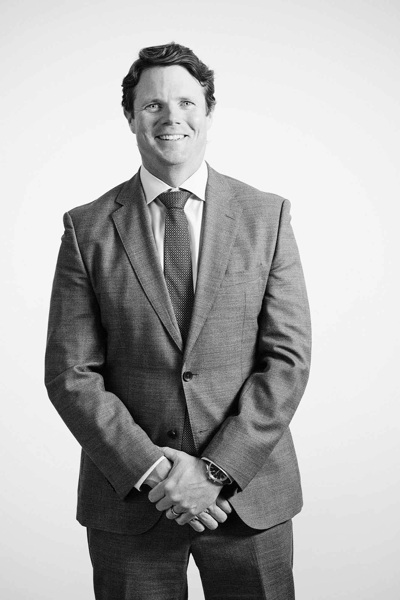 Black and white professional executive portrait of a man standing against a white background – Executive Portrait Photographer Copenhagen