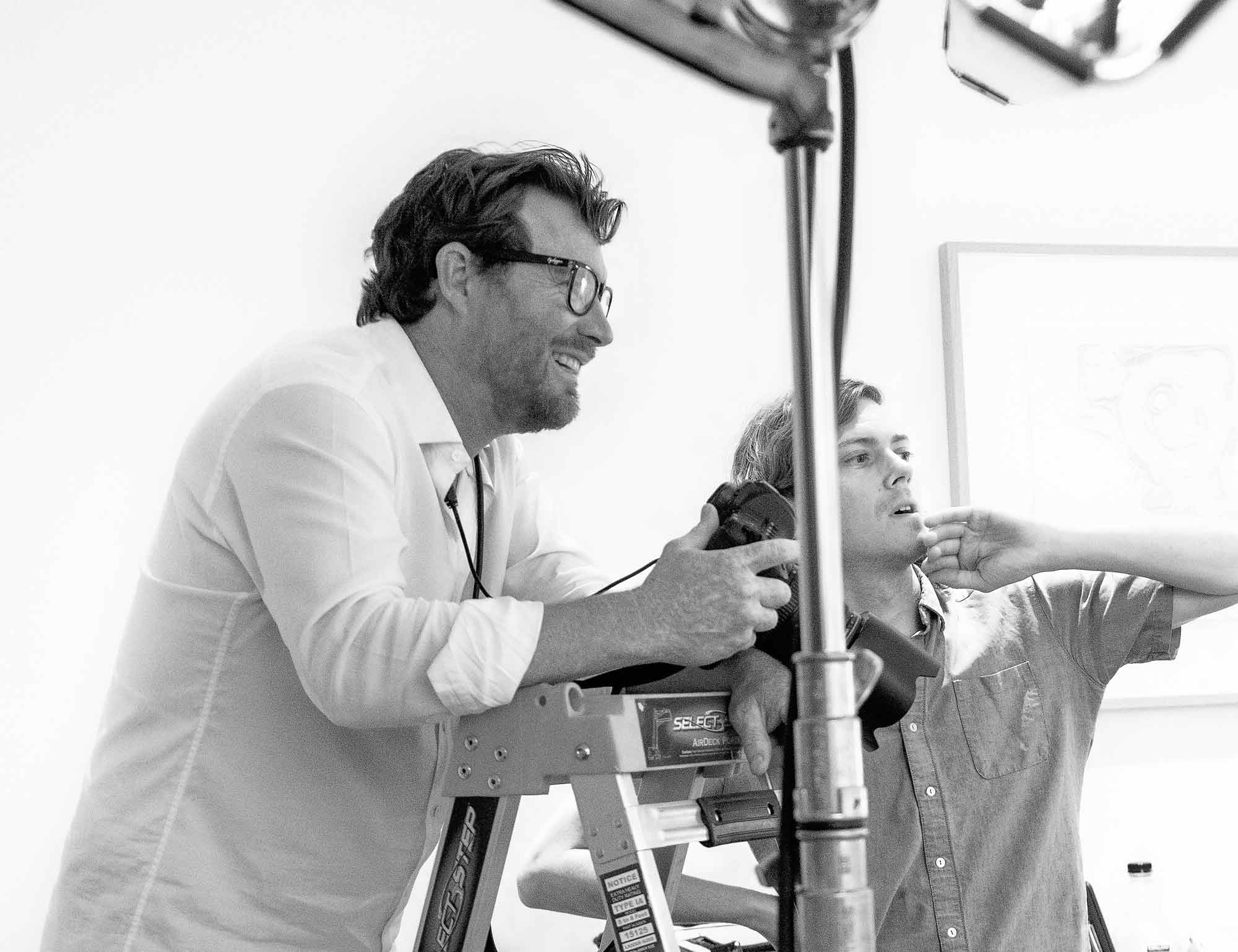 Executive portrait photographer directing subject during a professional photoshoot in a studio setting
